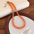 Detail der facettierten orangefarbenen Steinkette mit silbernem Verschluss auf Leinen - Orange