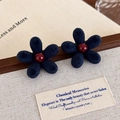Detalle de pendientes de flores de terciopelo azul marino con perla roja en un joyero - Pendientes de Botón de Flor Azul (27504D) / Azul
