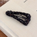 Detailed close-up of the vintage knitted wool texture on a triangular metal BB hair clip - Black