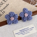 Primo piano di orecchini a fiore fatti a mano in maglia con lana blu-grigio e rosa - Fiore Blu