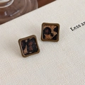 Dettaglio di orecchini vintage quadrati con trama leopardata e cornice marrone scuro - Stile quadrato marrone