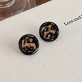 Gros plan de boucles d'oreilles léopard rondes avec bord noir sur fond texturé - Rond Noir