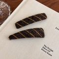 Detailed close-up of brown plush hair clips with yellow diagonal stripes on a book - Brown Yellow Stripe (27529D) / Brown