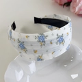 Vue détaillée d'un serre-tête floral avec roses bleues sur une assiette décorative - Fleur Bleue