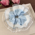 Détail d'un chouchou bleu à carreaux avec dentelle à pois blancs sur plateau beige - Bleu