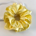 Gros plan d'un chouchou en satin jaune vif sur un plateau blanc aux textures douces - Style Plissé en Satin Jaune Vif (26836A)