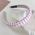 Detail eines handgefertigten cremefarbenen Haarreifs mit rosa Punkten und Label - Schmales Punktemuster / Rote Punkte