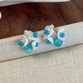 Gros plan détaillé de boucles d'oreilles fleurs vert menthe avec pétales blancs et perles - Boucles d'oreilles clous bouquet de muguet