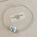 Détail du collier de perles vert menthe avec pendentifs fleurs de muguet blancs - Collier muguet vert menthe