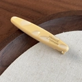 Dettaglio macro della clip per capelli a baguette francese in acetato con base in metallo dorato - Beige Multicolore