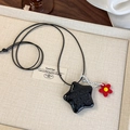 Détail macro du collier étoile noire avec texte et breloque fleur rouge pour femme - Étoile Noire