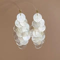 Detailed macro view of layered white pearlescent shell discs with golden bead ear hooks - White