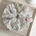 Gros plan d'un chouchou à pois blancs avec bords à volants et bouton cœur rouge - Blanc