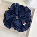 Détail d'un grand chouchou bleu marine à pois avec étiquette tissée à la main - Bleu