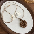 Détail d'un collier bohème montrant des perles en bois et un pendentif lune en cœur tissé - Disque Rond / Disque Rond Couleur Foncée