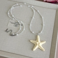 Gros plan du pendentif étoile de mer avec perles et perles de cristal sur boîte en lin - Perles Transparentes Étoile Beige (27048C)