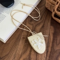 Détail du collier pochette étoile de mer tressé crème avec perles sur bois foncé - Beige