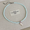 Vista detallada del collar de cuentas azul claro con cuenta rosa y un colgante de pez - Cuentas Azules