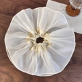 Detailed view of oversized off-white organza scrunchie with layered ruffles on a dark wood surface - Off White