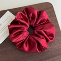 Close-up of deep red satin scrunchie with detailed rose floral embossing and smooth texture - Burgundy