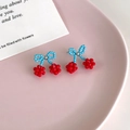 Süße blau-rote Kirsch-Ohrringe mit Perlenbogen auf einem rosa Ästhetik-Tablett - Kirsche Stil