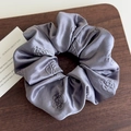 Dettaglio dell'elastico in raso grigio con goffratura di camelia su base in legno - Grigio