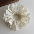 Detail of off-white lace hair scrunchie with intricate eyelet embroidery and wavy edges - Beige