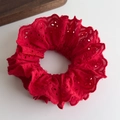 Detailed close-up of red lace scrunchie with intricate floral embroidery and cotton texture - Red