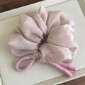 Detailopname van roze chiffon haarelastiekje met geweven knoop in een geschenkdoosje - Donkerroze