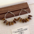 Detalle de pendientes de aro vintage con cuentas de resina ámbar en soporte de madera - Aro de Cuentas Retro Francés / Marrón Mixto
