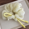 Macro-detail van crème chiffon scrunchie met een gele satijnen strik op een presenteerblad - Geel