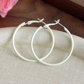 Close-up of cream-colored matte finish large hoop earrings on a textured tray - Off White