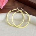 Detailed view of yellow macaron hoop earrings on white fabric background with flowers - Yellow