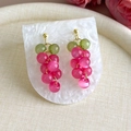 Vue macro de boucles d'oreilles grappe avec perles roses et vertes et métal doré brillant - Rose