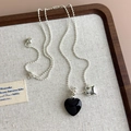 Detail of a silver bead chain necklace featuring black and silver heart pendants on a linen tray - Black Heart