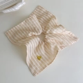Dettaglio dell'elastico per capelli a righe beige e bianche con ciondolo a fiocco dorato - Quadri Giallo