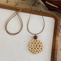 Macro shot of ethnic hand-woven beige beaded flower pendant with a brown wooden bead - Hollow Round Woven Style (27039C)