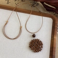 Close-up of brown beaded disk pendant on adjustable waxed cord in vintage ethnic style - Dark Beaded Round Style (27039D)