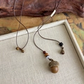Détail du collier pendentif gland avec perles en bois sur plateau en lin zen - Style Petit Gland (27174C)