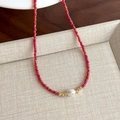 Dettaglio macro della collana di perline rosse con perla centrale e distanziali dorati - Perline Rosse