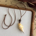Gros plan d'un collier bohème avec pendentif en coquillage naturel et perle en bois brun - Style Coquillage Long (26934C)