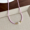 Dettaglio macro di una collana di perline rosa con una grande perla bianca e oro - Perline Rosa Viola