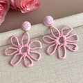 Detailansicht handgefertigter rosa Strohblumen-Ohrringe mit goldenen Metallringen - Rosa