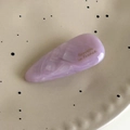 Macro view of a lavender acetate barrette with gold lettering on a ceramic tray - Purple Multi-color
