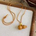 Détail d'un pendentif en bois en forme de gourde avec cordon orange et perle dorée - Style Gourde en Bois Massif (26109A)