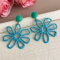 Detail von handgefertigten Stroh-Blumenohrringen in Blau und Grün für den Strandurlaub - Blau
