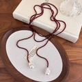 Dettaglio di collana vintage con perline rosso scuro e grandi perle barocche su legno - Rosso