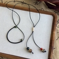 Détail d'un collier ethnique tissé avec perles en céramique et cordon noir sur bois - Collier Tissé Perlé Multi-matériaux (25683A)