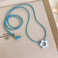 Detailaufnahme des blauen Blumenanhängers mit Kordel auf einem Vintage-Display - Blaue Schnur Halskette Mit Ausgehöhltem Blumenanhänger (9# 26750E)