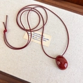 Dettaglio del ciondolo a ciottolo rosso lucido su una collana minimalista in cordino rosso - Borgogna